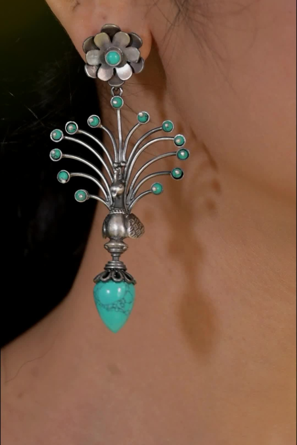 Silver and turquoise earring worn on an ear