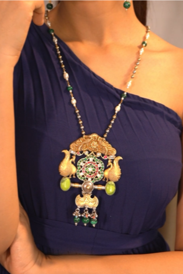 ornate necklace featuring green beads and a large pendant.