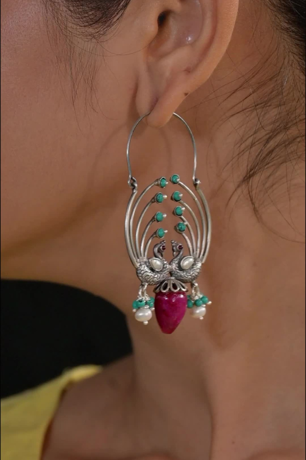 An ornate earring with turquoise and pink beads.