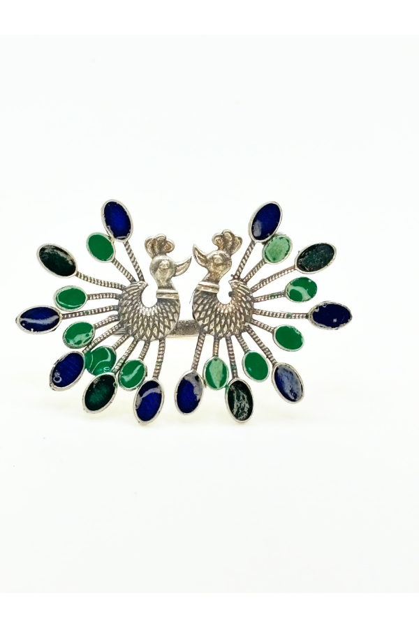 Decorative brooch with peacock design and colorful stones on a white background