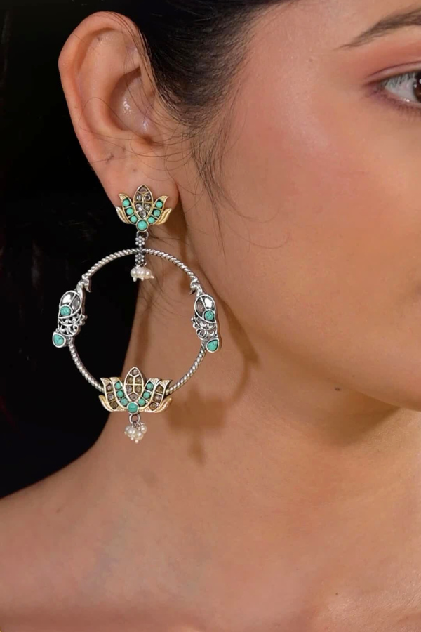 pair of silver hoop earrings with green gemstones.